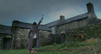 Movie still from “Withnail & I” (1987), directed by Bruce Robinson – A person holding a remote in a field; Extreme Wide shot, Low angle