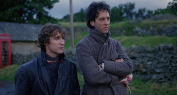 Movie still from “Withnail & I” (1987), directed by Bruce Robinson – Two men standing next to each other on a field; Medium shot, Low angle