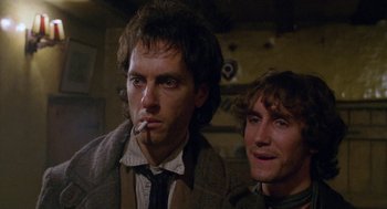 Movie still from “Withnail & I” (1987), directed by Bruce Robinson – A man smoking a cigarette next to another man; Close Up shot, Low angle