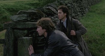 Movie still from “Withnail & I” (1987), directed by Bruce Robinson – Two men are climbing up a stone wall; Medium shot, High angle
