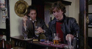 Movie still from “Withnail & I” (1987), directed by Bruce Robinson – Two men sitting at a bar with glasses of alcohol; Medium shot, Low angle