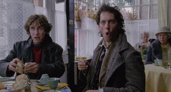 Movie still from “Withnail & I” (1987), directed by Bruce Robinson – Two men sitting at a table with a cup of coffee; Medium shot, Low angle
