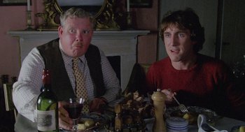 Movie still from “Withnail & I” (1987), directed by Bruce Robinson – Two men sitting at a dinner table with food; Medium shot, Low angle
