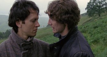 Movie still from “Withnail & I” (1987), directed by Bruce Robinson – Two men standing next to each other on a grassy hill; Close Up shot, Over the shoulder angle