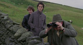 Movie still from “Withnail & I” (1987), directed by Bruce Robinson – A man looking through binoculars while two other men look on; Medium shot, Over the shoulder angle