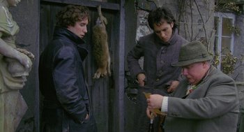 Movie still from “Withnail & I” (1987), directed by Bruce Robinson – A group of men standing next to each other near a door; Medium shot, Over the shoulder angle