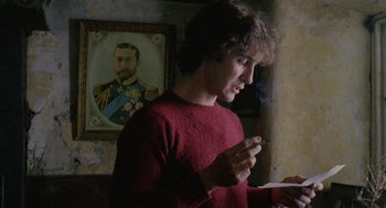 Movie still from “Withnail & I” (1987), directed by Bruce Robinson – A man in a red shirt is holding papers; Medium shot, Over the shoulder angle