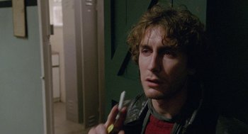 Movie still from “Withnail & I” (1987), directed by Bruce Robinson – A young man holding a cell phone in his hand; Close Up shot, Over the shoulder angle