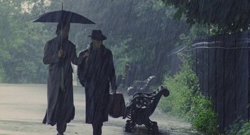 Movie still from “Withnail & I” (1987), directed by Bruce Robinson – Two people walking down a street in the pouring rain; Wide shot, Low angle