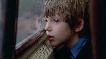Movie still from “Witness” (1985), directed by Peter Weir – A young boy looking out a train window; Close Up shot, Low angle