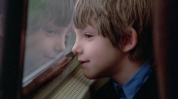 Movie still from “Witness” (1985), directed by Peter Weir – A young boy looking out of a train window; Close Up shot, Over the shoulder angle