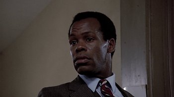 Movie still from “Witness” (1985), directed by Peter Weir – A man in a suit and tie looking to his left; Close Up shot, Low angle