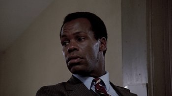 Movie still from “Witness” (1985), directed by Peter Weir – A man in a suit and tie looking to his left; Close Up shot, Low angle