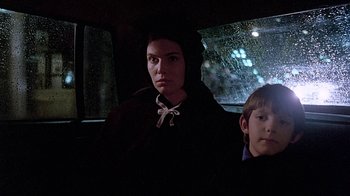 Movie still from “Witness” (1985), directed by Peter Weir – A woman and a boy sitting in the back of a car; Close Up shot, Over the shoulder angle