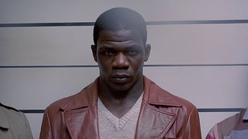 Movie still from “Witness” (1985), directed by Peter Weir – A man in a brown leather jacket and a white shirt; Close Up shot, High angle