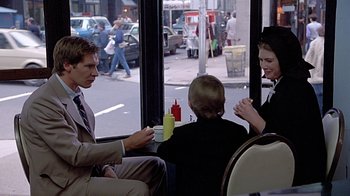 Movie still from “Witness” (1985), directed by Peter Weir – A group of people sitting on a bus eating food; Medium shot, Over the shoulder angle