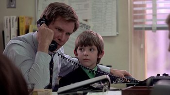 Movie still from “Witness” (1985), directed by Peter Weir – A man and a boy sitting at a desk with a phone; Close Up shot, Low angle