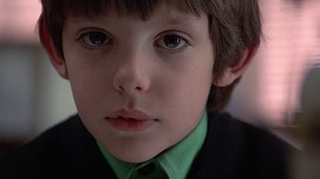 Movie still from “Witness” (1985), directed by Peter Weir – A young boy wearing a green shirt; Close Up shot, Low angle