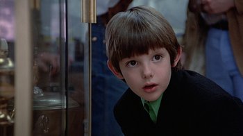 Movie still from “Witness” (1985), directed by Peter Weir – A young boy in a black jacket and green shirt; Close Up shot, Over the shoulder angle