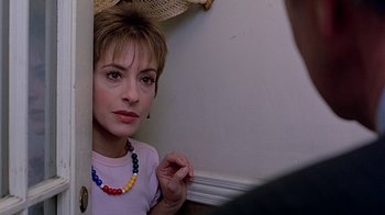 Movie still from “Witness” (1985), directed by Peter Weir – A person wearing a necklace near a wall; Close Up shot, Over the shoulder angle