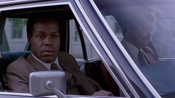 Movie still from “Witness” (1985), directed by Peter Weir – A man sitting in the passenger seat of a car; Close Up shot, Over the shoulder angle