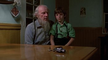 Movie still from “Witness” (1985), directed by Peter Weir – An older man and a young boy sitting at a table; Medium shot, Over the shoulder angle