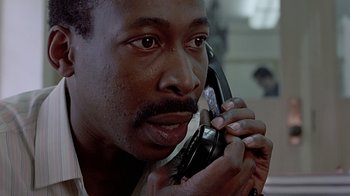 Movie still from “Witness” (1985), directed by Peter Weir – A person talking on a cell phone; Close Up shot, Low angle