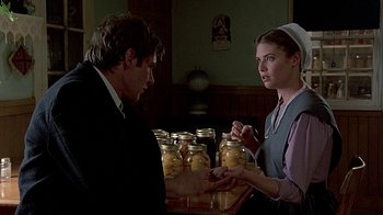 Movie still from “Witness” (1985), directed by Peter Weir – A man and a woman are looking at a jar of food; Medium shot, Low angle