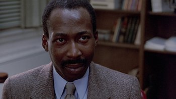 Movie still from “Witness” (1985), directed by Peter Weir – A person wearing a suit and tie; Close Up shot, Over the shoulder angle