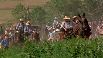 Movie still from “Witness” (1985), directed by Peter Weir – A group of men riding on the back of a horse drawn carriage; Extreme Wide shot, High angle