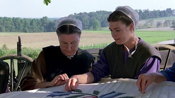 Movie still from “Witness” (1985), directed by Peter Weir – Two women sitting at a table looking at papers; Medium shot, High angle