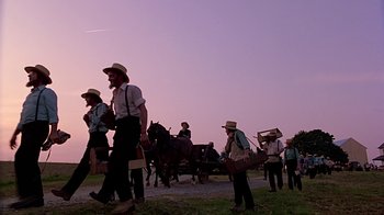 Movie still from “Witness” (1985), directed by Peter Weir – A group of men walking down a road with horses; Wide shot, Low angle