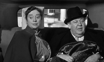 Movie still from “Witness for the Prosecution” (1957), directed by Billy Wilder – An old photo of an older man and a woman in a car; Medium shot, High angle