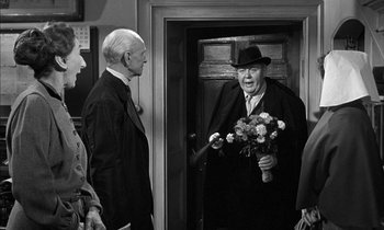 Movie still from “Witness for the Prosecution” (1957), directed by Billy Wilder – An older man holding a bouquet of flowers in his hand; Medium shot, Over the shoulder angle