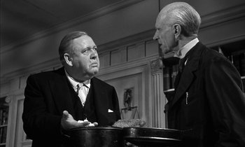 Movie still from “Witness for the Prosecution” (1957), directed by Billy Wilder – Two older men in suits talking to each other; Close Up shot, Low angle