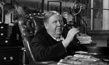 Movie still from “Witness for the Prosecution” (1957), directed by Billy Wilder – An older man sitting at a desk in an office; Close Up shot, High angle