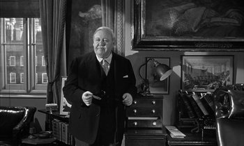 Movie still from “Witness for the Prosecution” (1957), directed by Billy Wilder – An older man in a suit and tie standing in front of a painting; Medium shot, Low angle