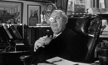 Movie still from “Witness for the Prosecution” (1957), directed by Billy Wilder – An older man sitting in a chair with his hand on his chin; Close Up shot, Over the shoulder angle
