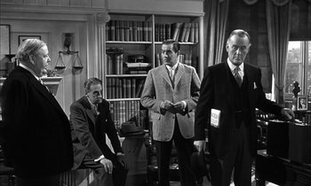 Movie still from “Witness for the Prosecution” (1957), directed by Billy Wilder – A group of men standing in front of a book case; Medium shot, Low angle