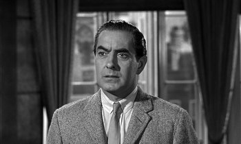Movie still from “Witness for the Prosecution” (1957), directed by Billy Wilder – A man wearing a suit and tie in front of a window; Close Up shot, Low angle