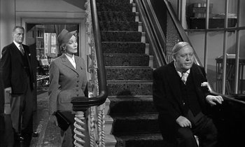Movie still from “Witness for the Prosecution” (1957), directed by Billy Wilder – An older man sitting on the stairs next to an older woman; Medium shot, High angle