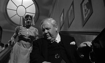 Movie still from “Witness for the Prosecution” (1957), directed by Billy Wilder – An older man sitting next to a young woman; Medium shot, Low angle