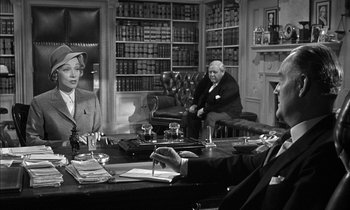Movie still from “Witness for the Prosecution” (1957), directed by Billy Wilder – A black and white photo of a group of people sitting at a table; Medium shot, Over the shoulder angle
