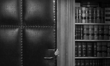 Movie still from “Witness for the Prosecution” (1957), directed by Billy Wilder – A hand is holding on to a book case; Medium shot, Over the shoulder angle