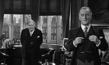 Movie still from “Witness for the Prosecution” (1957), directed by Billy Wilder – Two older men in suits and ties standing in a room; Medium shot, Over the shoulder angle
