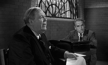 Movie still from “Witness for the Prosecution” (1957), directed by Billy Wilder – Two men sitting at a table in front of each other; Medium shot, Over the shoulder angle