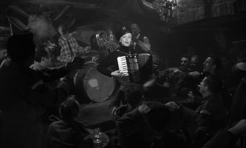 Movie still from “Witness for the Prosecution” (1957), directed by Billy Wilder – A man playing an accordion in front of a crowd; Wide shot, Low angle