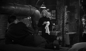 Movie still from “Witness for the Prosecution” (1957), directed by Billy Wilder – A black and white photo of a woman holding a towel; Wide shot, Over the shoulder angle