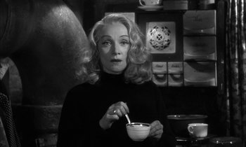 Movie still from “Witness for the Prosecution” (1957), directed by Billy Wilder – A woman holding a bowl of soup in a kitchen; Close Up shot, Over the shoulder angle