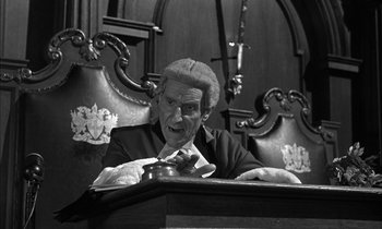 Movie still from “Witness for the Prosecution” (1957), directed by Billy Wilder – An old man sitting at a table with a phone; Medium shot, Low angle